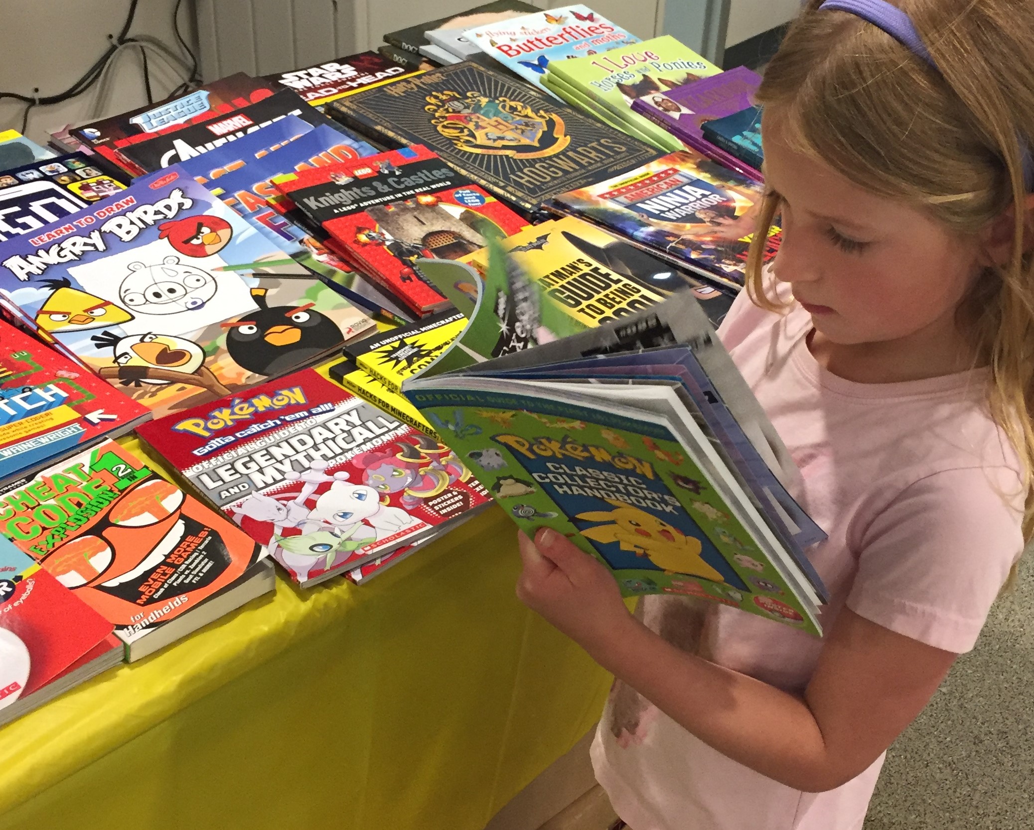 image of girl reading a book in front of table filled with books