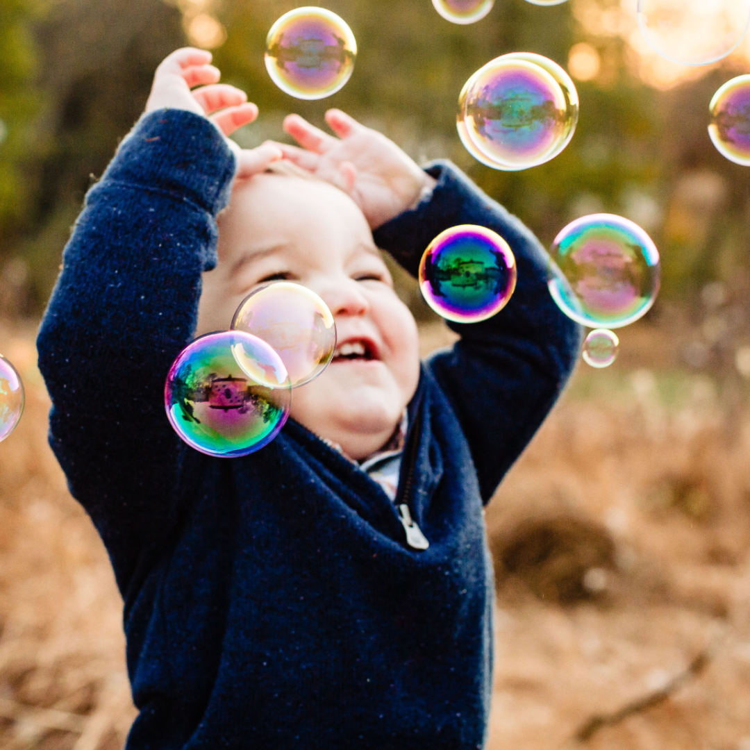 image of a small child playing with bubbles in the air