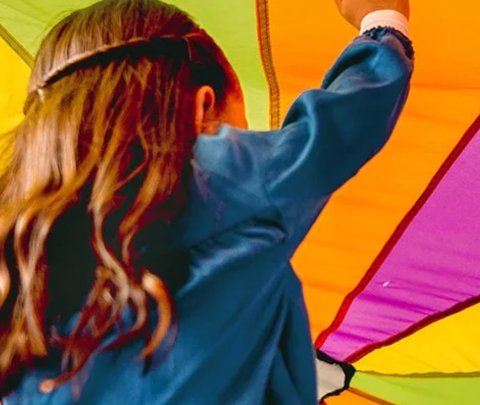 image of children playing under a parachute