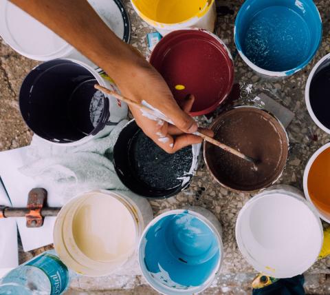 image of a hand dipping a paint brush in a paint container