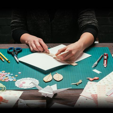 close up image of human hands working with scrapbooking tools