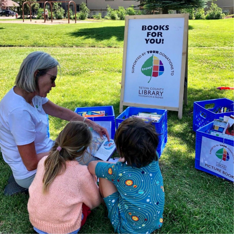 image of an adult reading a book to two children