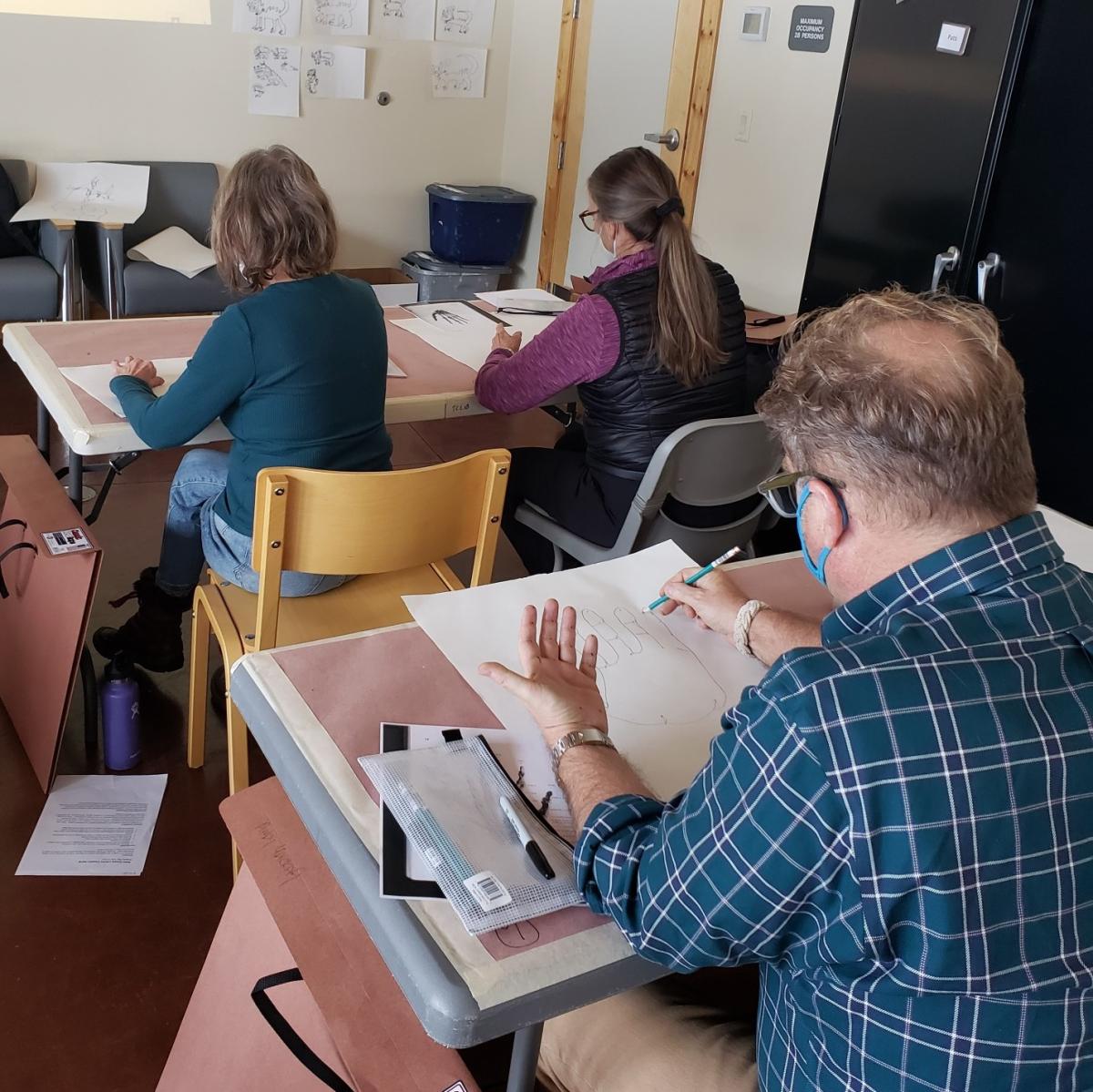 image of people drawing at tables