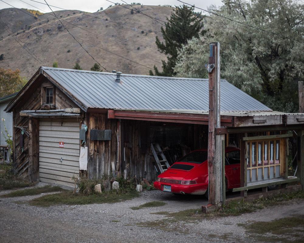 photo of funky old Jackson log house with a red Porsche parked next to it